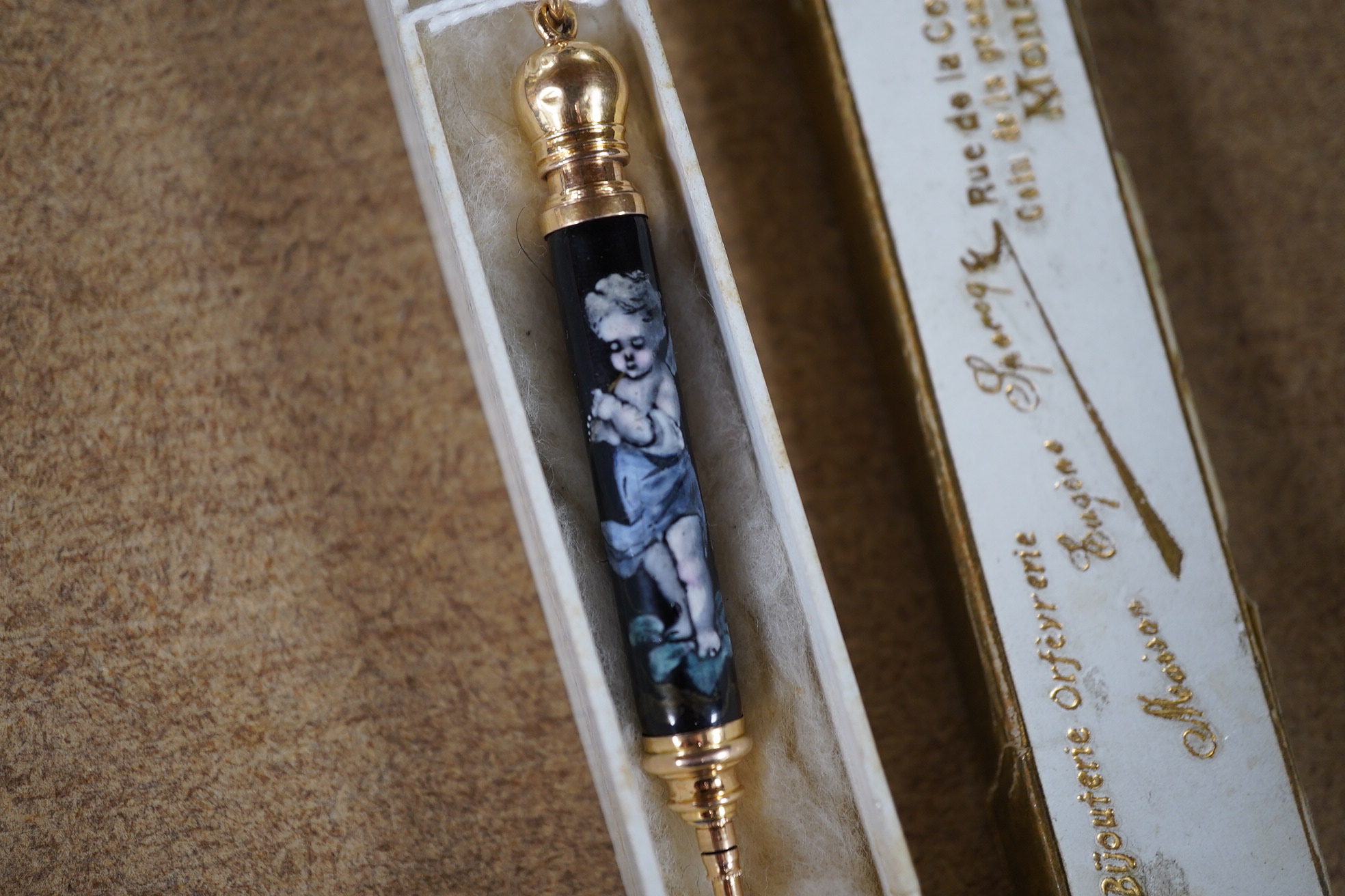 A Continental yellow metal and enamel propelling pencil decorated with putti, 72mm. Condition - poor (slight damage to the enamel).